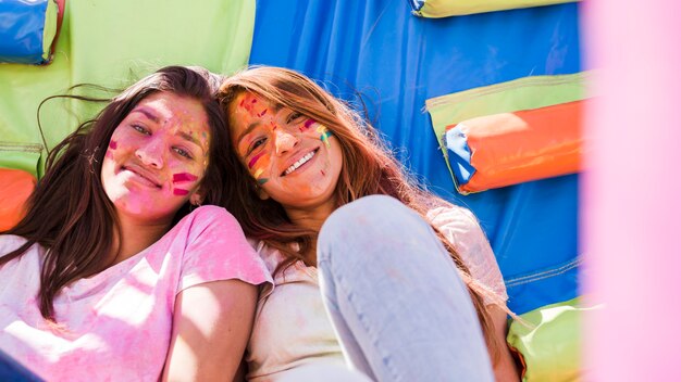 Porträt von lächelnde junge Frauen mit holi Farbfarbe auf ihrem Gesicht, das Kamera betrachtet