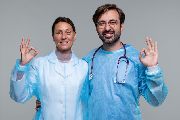 Porträt von Mann und Frau, die medizinische Kittel tragen und ein OK-Zeichen zeigen