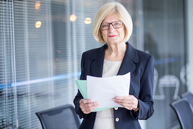 Kostenloses Foto porträt von positiven weiblichen manager mit dokumenten