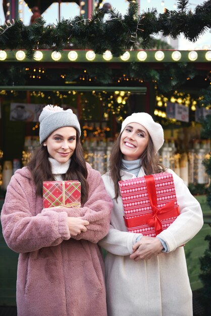 Porträt von zwei Frauen mit Geschenken auf dem Weihnachtsmarkt