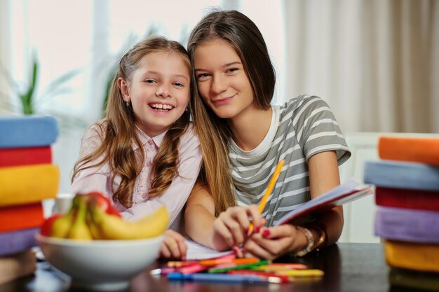 Porträt von zwei Freundinnen, die mit vielen Büchern am Tisch studieren.