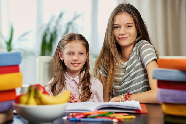 Porträt von zwei freundinnen, die mit vielen büchern am tisch studieren.