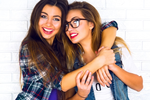 Porträt von zwei hübschen jugendlich Freundinnen, die lächeln und sich umarmen