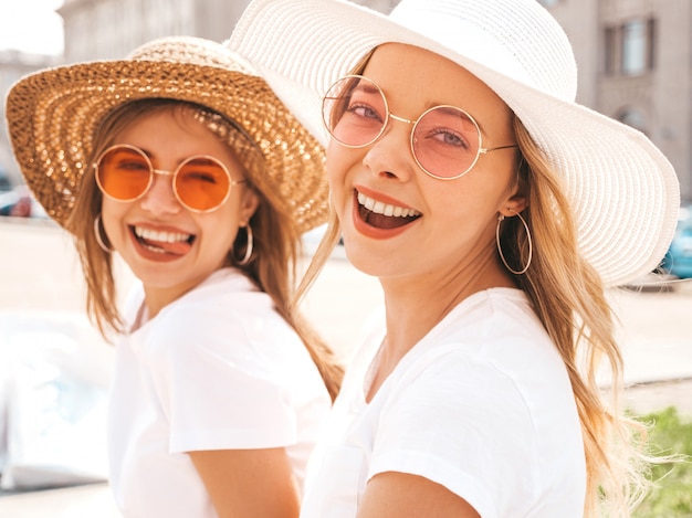 Porträt von zwei jungen schönen blonden lächelnden Hippie-Mädchen im weißen T-Shirt des modischen Sommers kleidet.