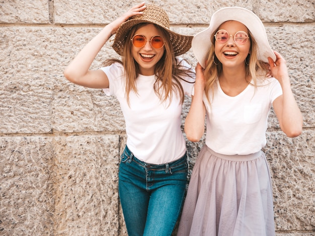 Porträt von zwei jungen schönen blonden lächelnden Hippie-Mädchen im weißen T-Shirt des modischen Sommers kleidet.