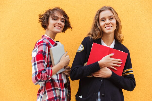 Porträt von zwei jungen Teenager-Mädchen mit Büchern stehend