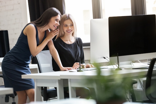 Kostenloses Foto porträt von zwei lächelnden geschäftsfrauen, die im büro arbeiten