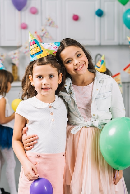 Porträt von zwei Mädchen, die zusammen mit bunten Ballonen stehen