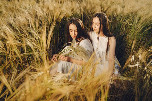 Porträt von zwei Schwestern in weißen Kleidern mit langen Haaren auf einem Feld