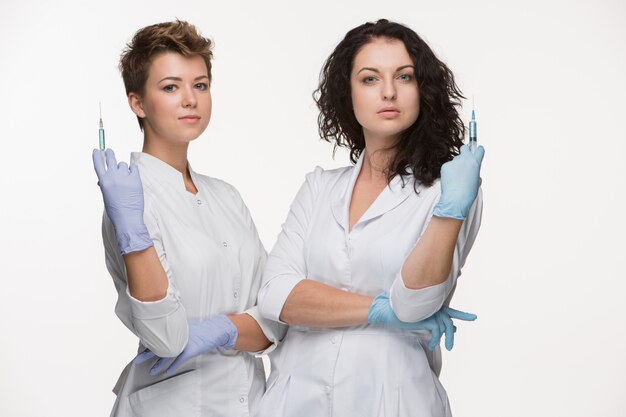 Porträt von zwei weiblichen Chirurgen, die Spritzen zeigen