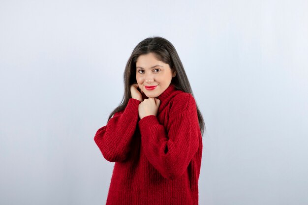 Porträtfoto eines jungen Frauenmodells im roten warmen Pullover, der steht und posiert