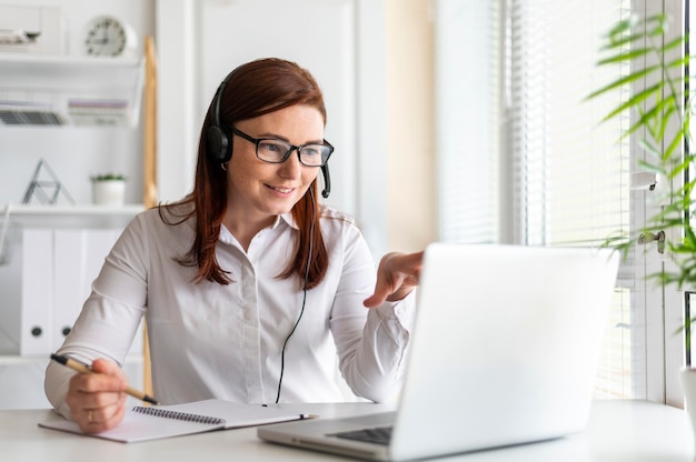 Porträtfrau bei der Arbeit, die Videoanruf auf Laptop hat