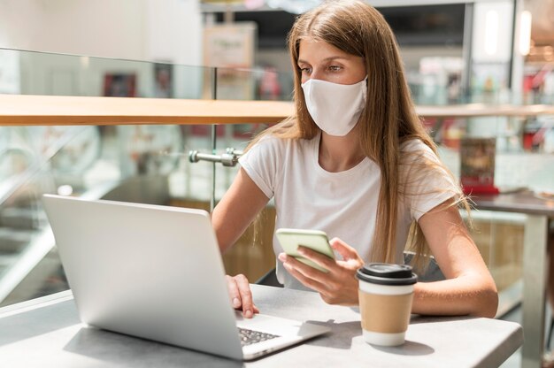 Porträtfrau, die am Laptop mit Maske arbeitet