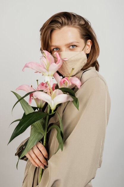 Porträtfrau, die Maske trägt und Blumenstrauß hält