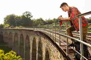 Kostenloses Foto porträtmann an der brücke mit fernglas