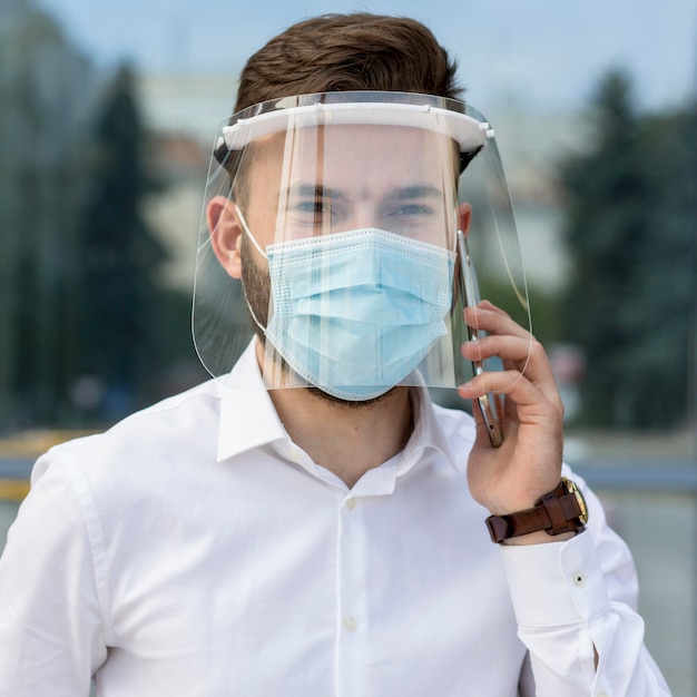 Porträtmann mit Maske, die über Telefon spricht