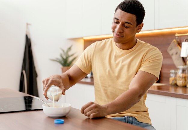 Porträtmann zu Hause, der Milch in Schüssel gießt