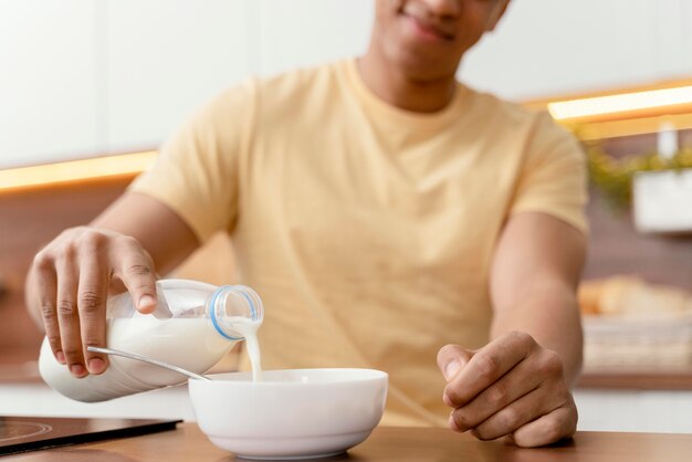 Porträtmann zu Hause, der Milch in Schüssel gießt