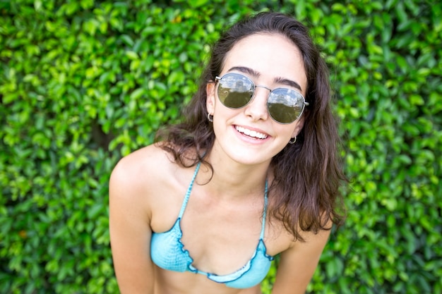 Portrait der freudigen Frau im Bikini und Sonnenbrille