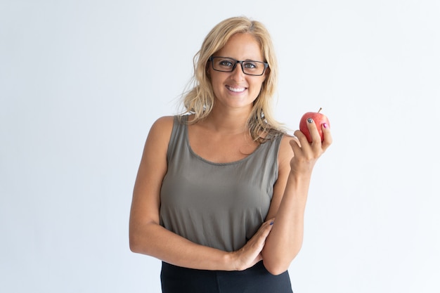 Portrait der glücklichen mittleren erwachsenen Geschäftsfrau in den Gläsern mit Apfel.