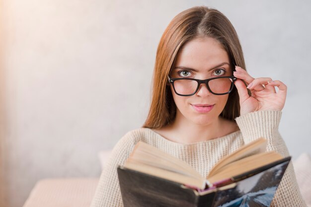 Portrait der jungen Frau reparierte Brillen, um Buch zu lesen