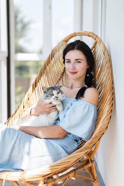 Portrait der jungen Frau sitzend mit ihrer Katze auf Stuhl