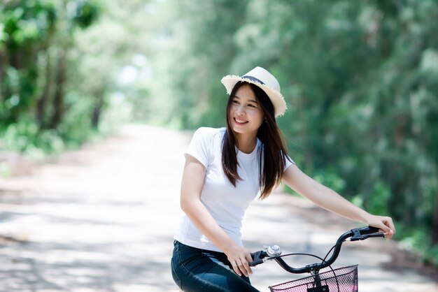 Portrait der jungen schönen Frau, die Fahrrad in einem Park fährt.