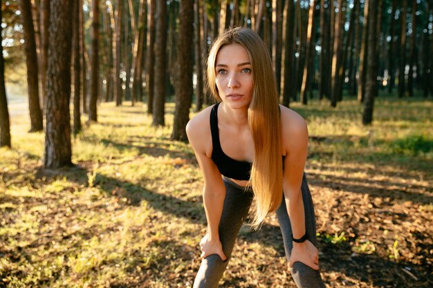 Portrait der jungen schönen Frau mit dem langen Haar in der Sportkleidung, die Übung im Park tut