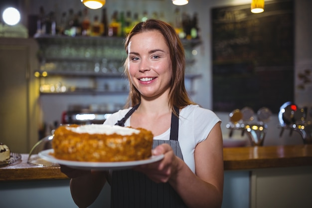 Portrait der Kellnerin, die einen Teller mit Kuchen halten
