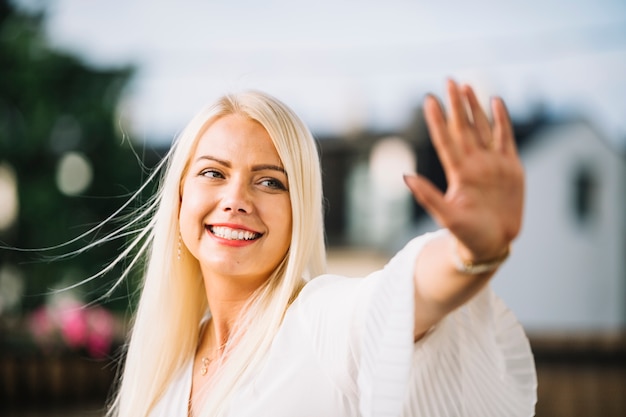 Portrait der lächelnden jungen Frau, die ihre Hand zeigt