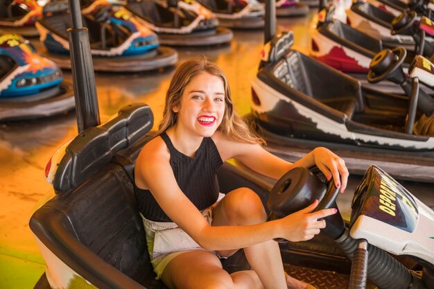 Portrait der lächelnden jungen Frau, die im Auto der Stoßstange sitzt