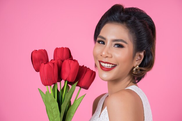 Portrait der schönen Frau mit Blumenstrauß der roten Tulpe blüht