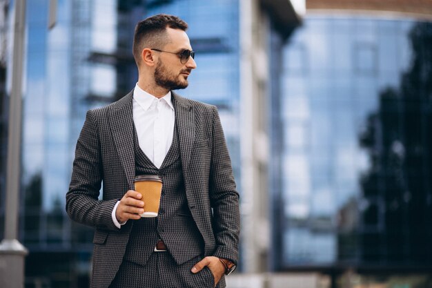 Portrait des Geschäftsmannes durch den trinkenden Kaffee des Wolkenkratzers