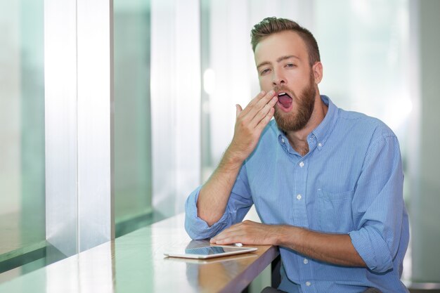 Portrait des jungen Managers im Büro Gähnen