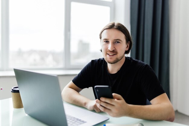 Portrait des jungen Mannes sitzend an seinem Schreibtisch im Büro