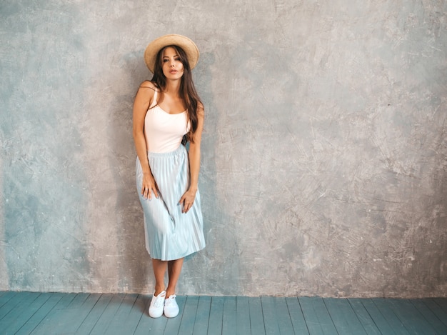 Portrait des jungen schönen Frauenschauens. Modisches Mädchen im zufälligen Sommerkleid und -hut.