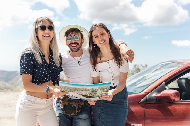 Kostenloses Foto portrait des mannes mit den weiblichen freunden, die nahe dem auto stehen