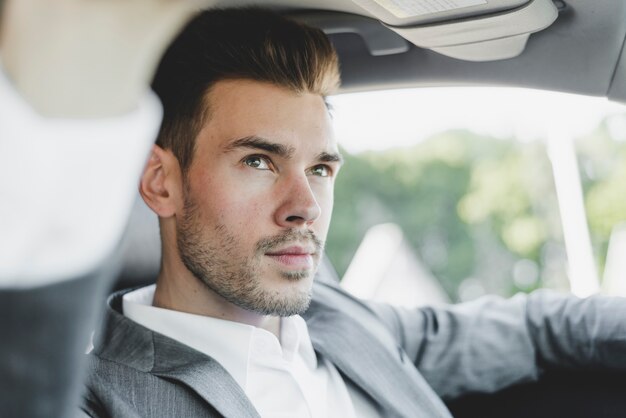 Portrait des stattlichen jungen Geschäftsmannes im Auto