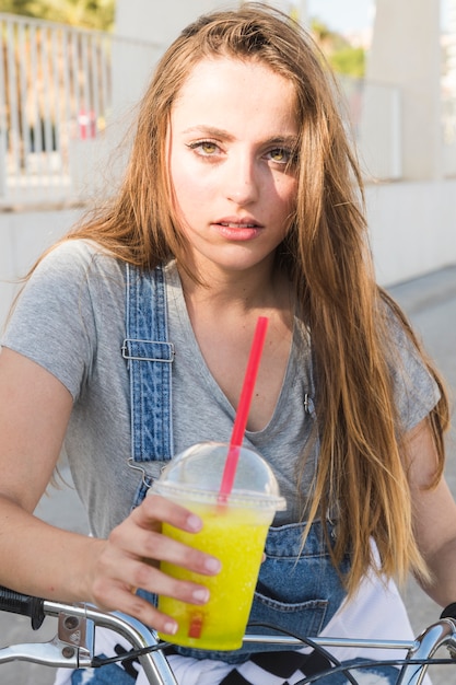 Portrait einer Frau mit dem Fahrrad, das Glas Saft anhält