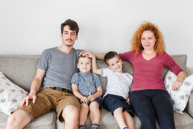 Portrait einer glücklichen Familie, die zu Hause auf Sofa sitzt