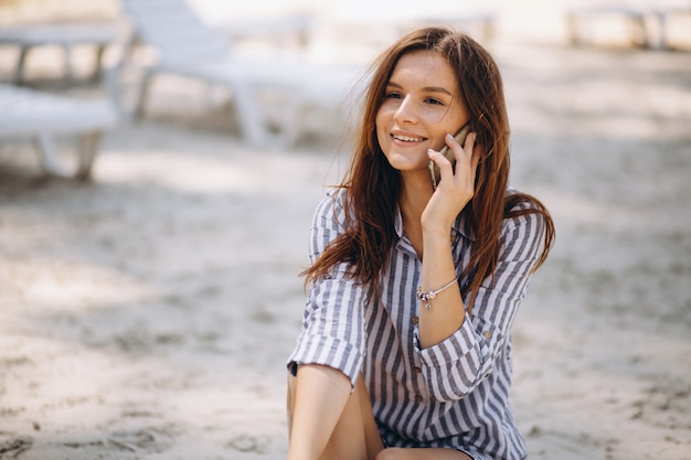 Portrait einer jungen Frau mit Telefon am Strand