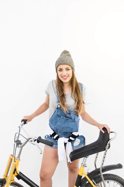 Portrait einer lächelnden jungen Frau mit Fahrrad gegen weißen Hintergrund