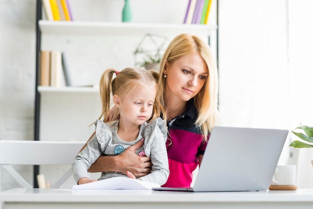 Portrait einer Mutter und der Tochter, die an Laptop arbeiten