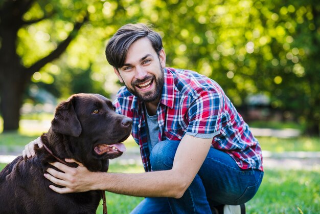 Portrait eines glücklichen jungen Mannes mit seinem Hund im Park