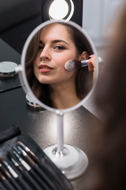 Portrait eines jungen Brunette, der Kosmetik aufträgt