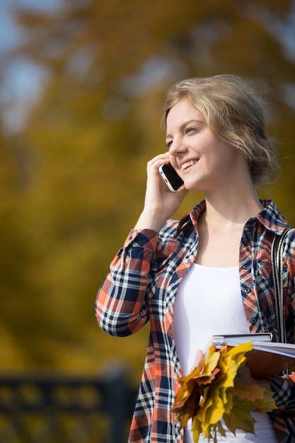 Portrait eines jungen lächelnden Studenten outsides, reden am Telefon