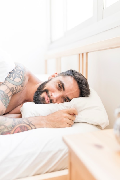 Portrait eines jungen Mannes, der auf Bett liegt