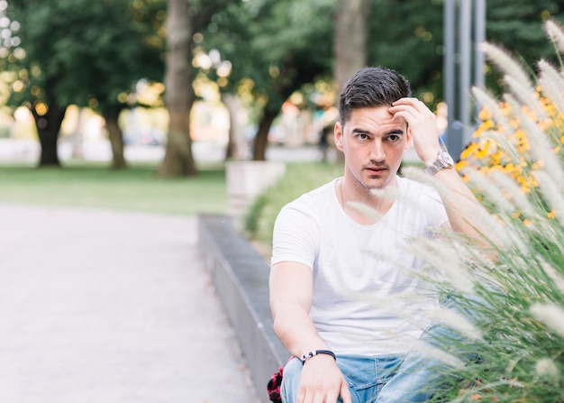 Portrait eines jungen Mannes, der im Garten sitzt