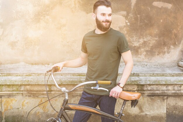 Portrait eines jungen Mannes mit dem Fahrrad, das weg schaut