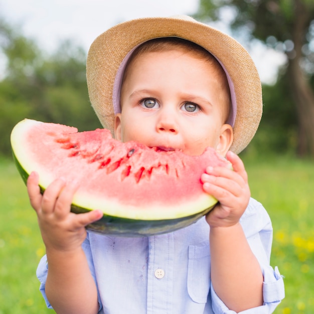 Portrait eines Jungen mit den grauen Augen, die Wassermelone essen